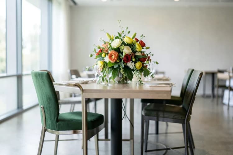 Cadeira de banquete e mesa decorada com arranjo floral.