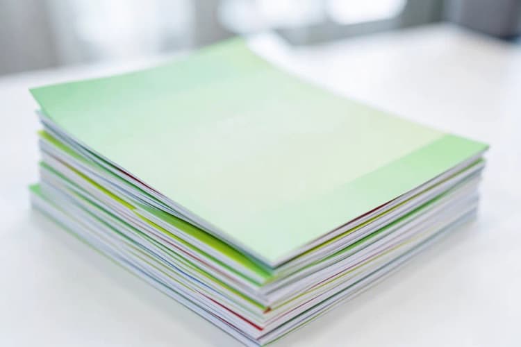 Pilha de papéis impressos e dobrados, prontos para retirada em uma gráfica.
