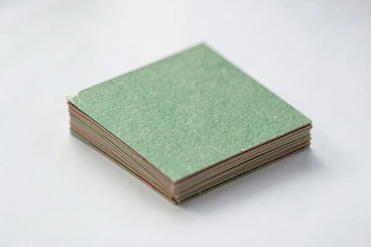 Uma pilha de cartões de visita em papel reciclado texturizado, com bordas levemente irregulares.