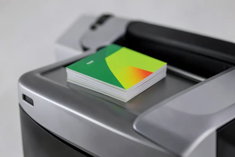 Um conjunto de cartões de visita empilhados em cima de uma máquina de impressão moderna, com foco na qualidade do material gráfico.