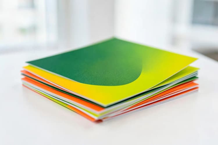 Pilha de papéis impressos com cores vibrantes, mostrando a qualidade da impressão.