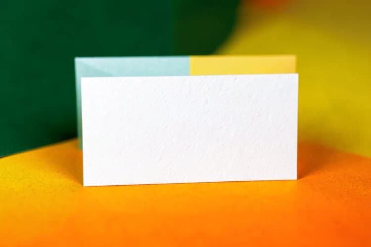 Close-up de um cartão de visita branco com texto preto, mostrando detalhes da impressão.