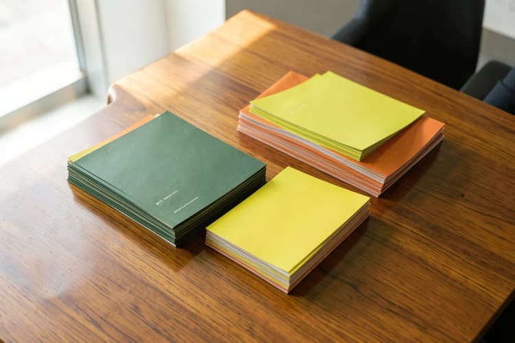 Uma pessoa organizando panfletos em pilhas de diferentes tamanhos em uma mesa de madeira.