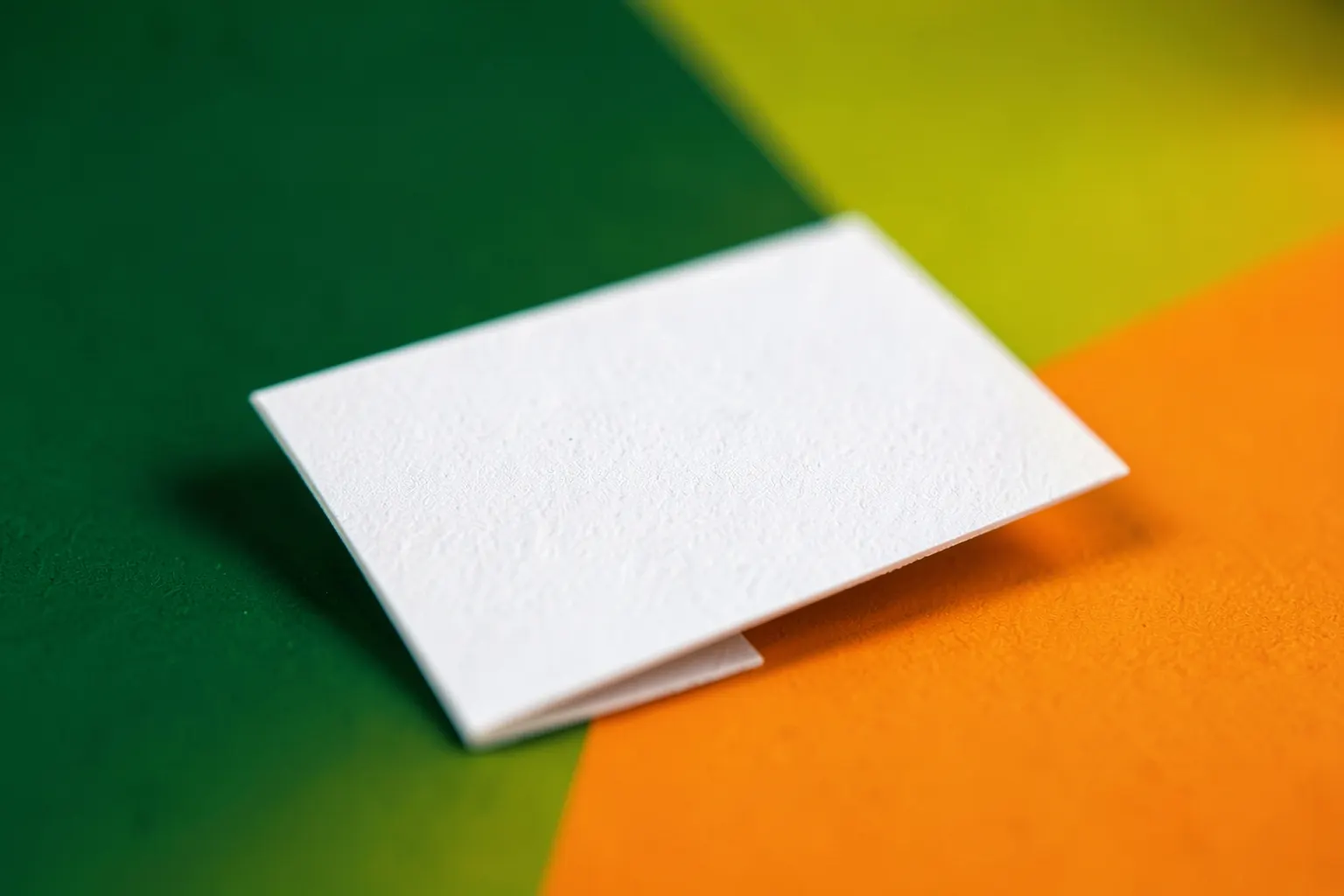 Close-up de um cartão de visita branco com textura sutil, em um fundo neutro.